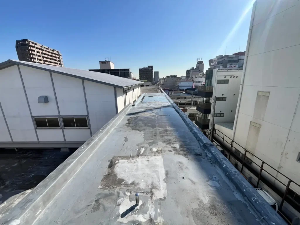 雨漏りの原因となる屋上の水たまりと、経年劣化でバリバリに割れてしまった防水シートの様子