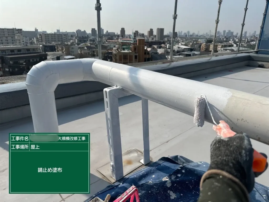 配管に白い錆止め塗料を塗布している様子